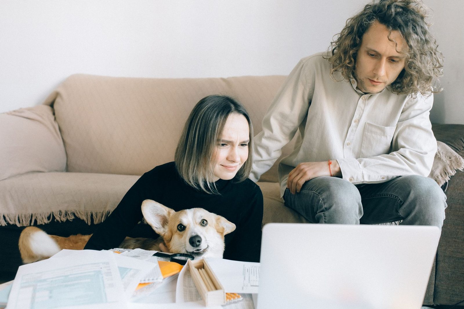 Couple reviewing documents on a laptop with their dog nearby