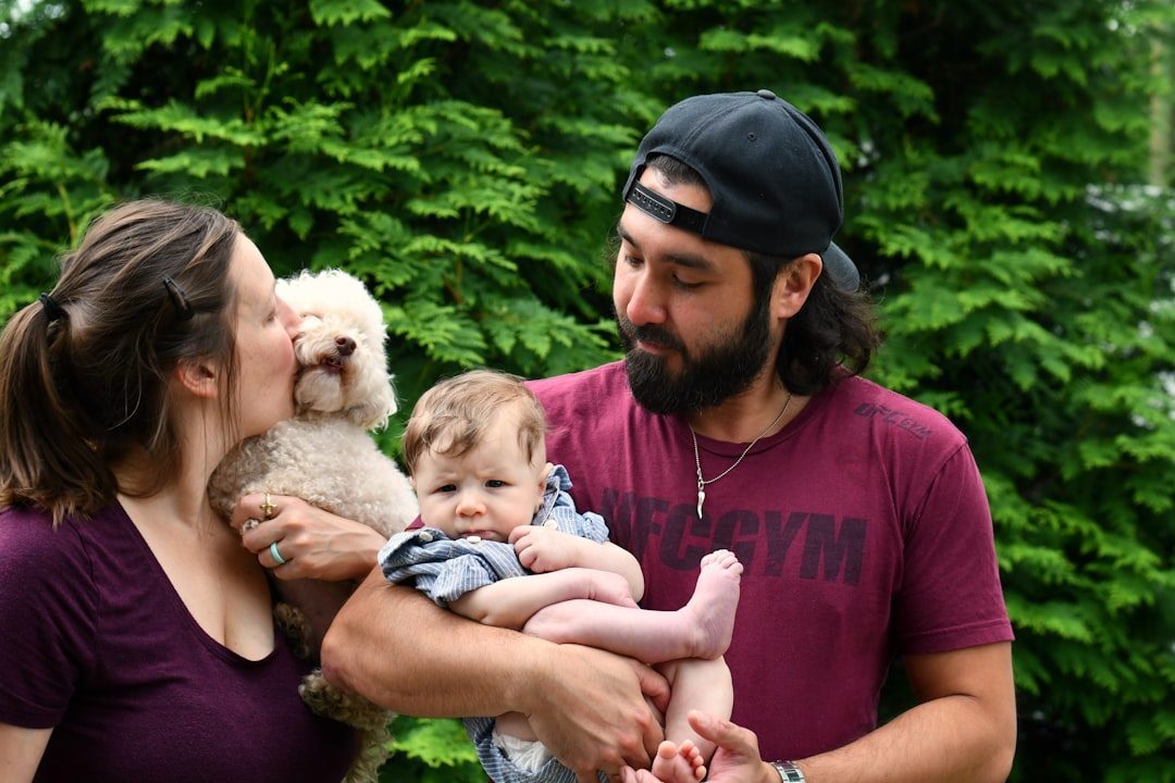 Parents holding a baby and a small puppy together outdoors