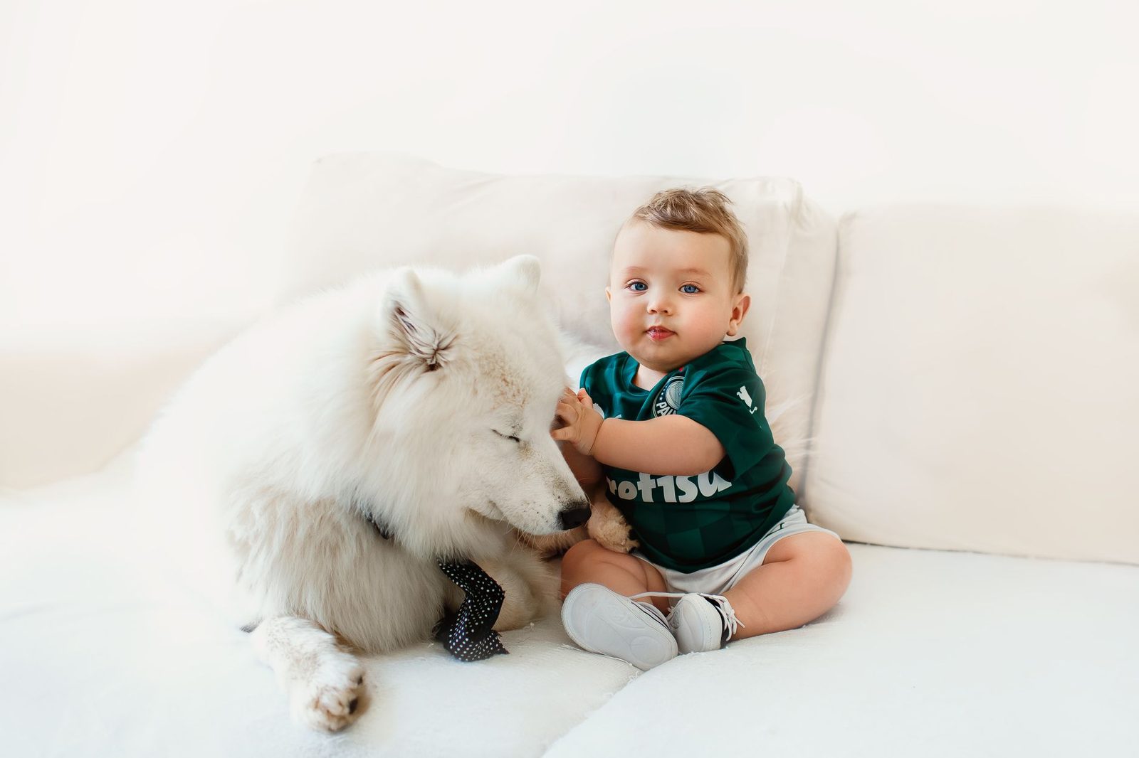 Parent supervising a large fluffy dog lying calmly near a baby on a blanket